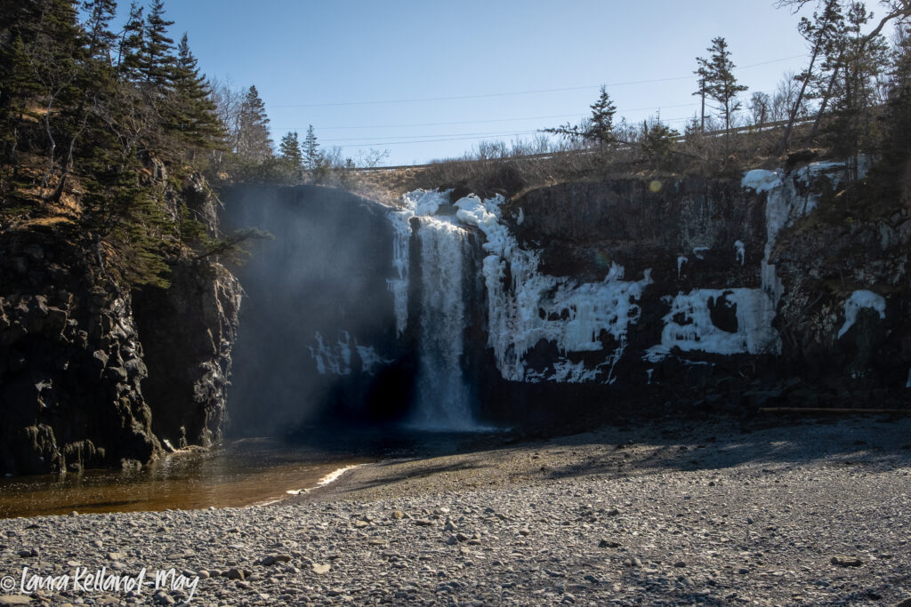 Water falls with ice and snow falling into a pool at low tide at the beach